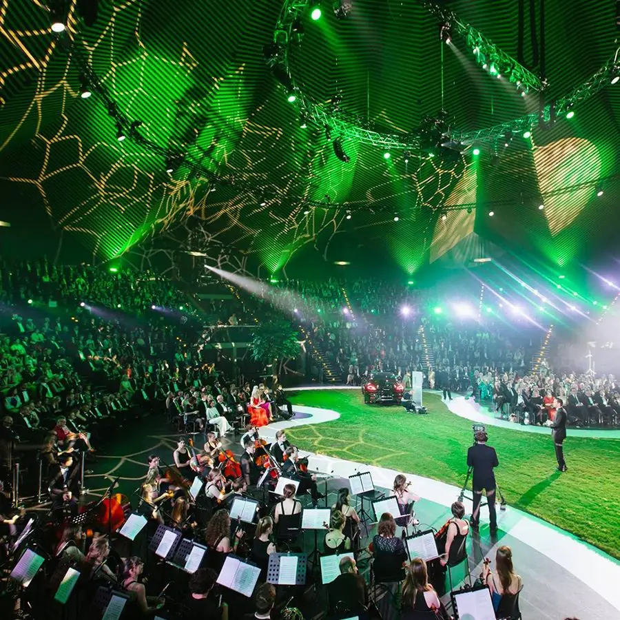 An orchestra on stage under a canopy of green light