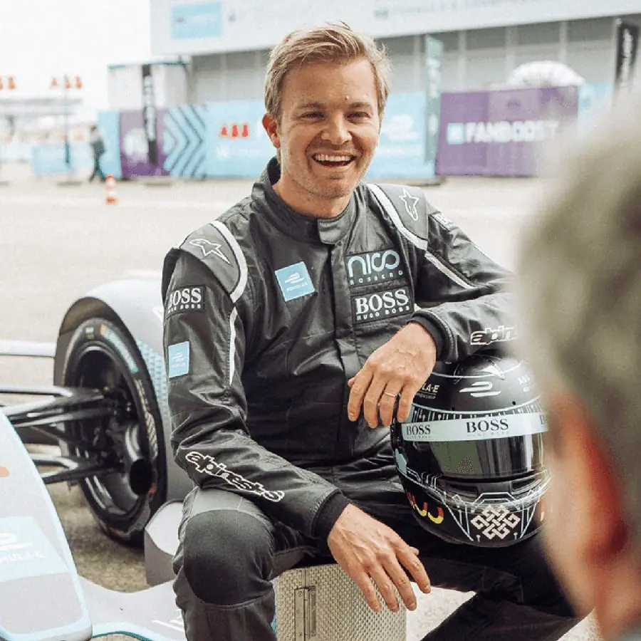 A driver in racing overalls in the Formula E paddock