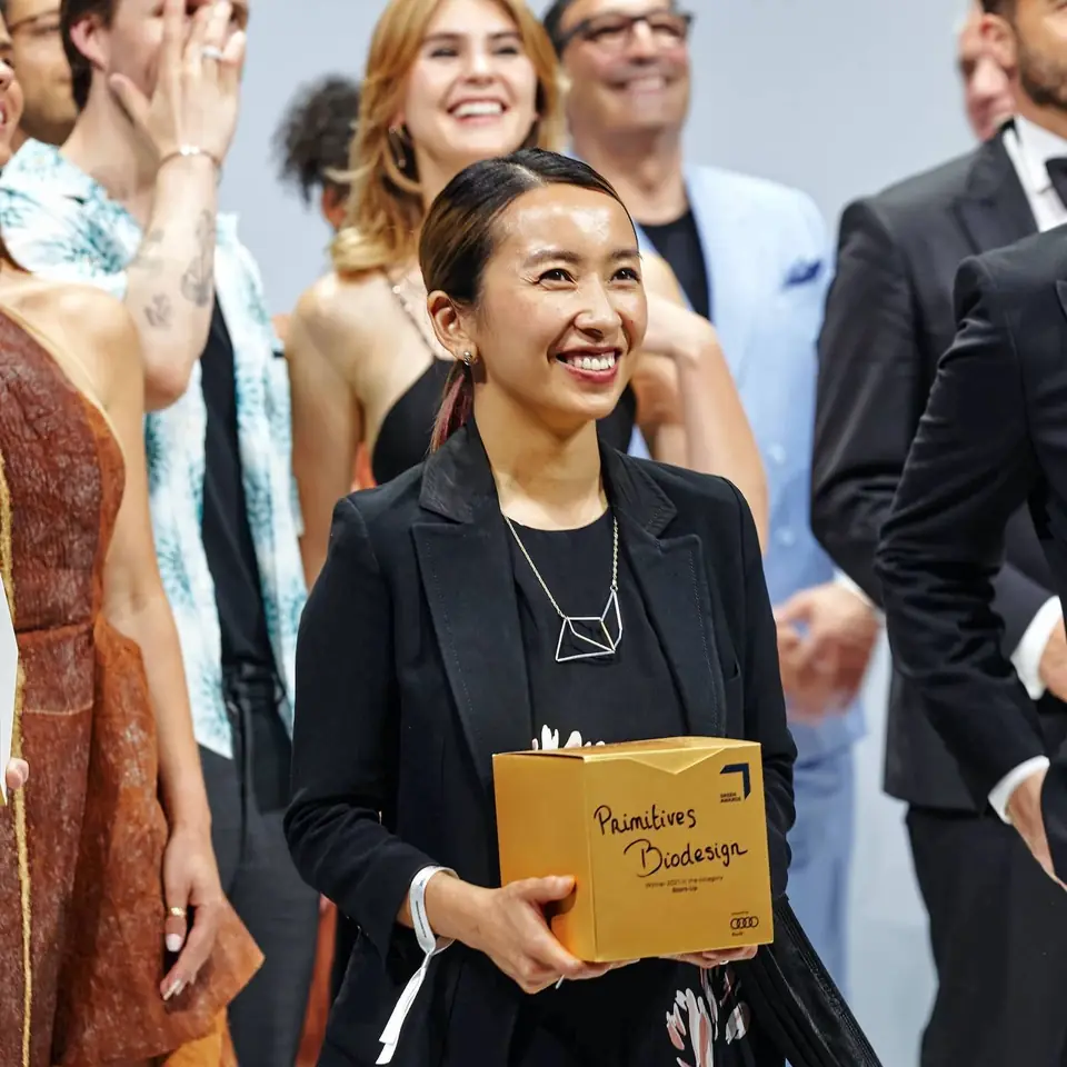 A GREEN AWARDS winner holding the trophy on the carpet
