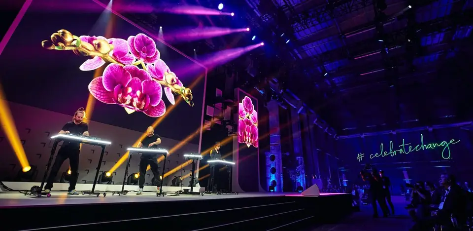 Performers on stage under projected orchids