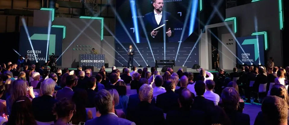 A speaker on the Green Beats stage in front of a seated audience