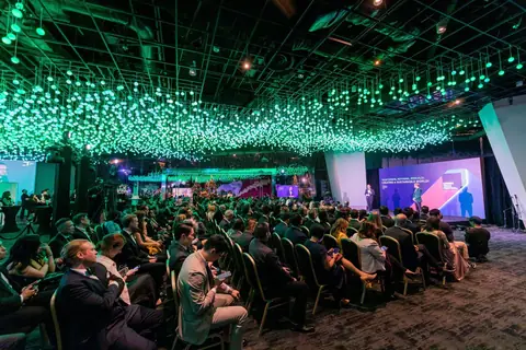 The audience seated under the green light canopy of the 2023 Berlin edition